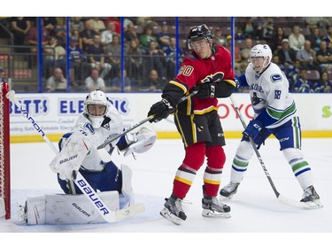 Calgary Flames Glenn Gawdin (middle) tries to redirect the puck past Vancouver Canucks goalie Michael DiPietro.