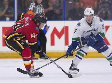 Calgary Flames Rasmus Andersson (left) tries to settle the puck while pressured by Vancouver Canucks Brock Boeser.