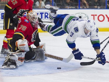 Vancouver Canucks Griffen Molino (right) falls to the ice after getting stopped by Calgary Flames goalie Nick Schneider.