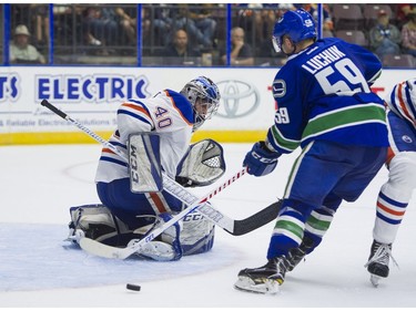 Vancouver Canucks Aaron Luchuk (right) tries to get a stick on the loose puck after Edmonton Oilers goalie Shane Starrett made the initial save.