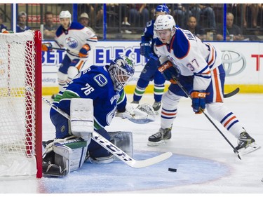 Edmonton Oilers Grayson Pawlenchuk (right) tries to get a stick on the loose puck after Vancouver Canucks goalie Michael Garteig made a save.