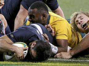 Argentina's Martin Landajo, left, scores a try despite the defensive efforts of Australia's Scott Sio, and Ned Hanigan, right, during their rugby union test match in Canberra, Saturday, Sept. 16, 2017. (AP Photo/Rick Rycroft)