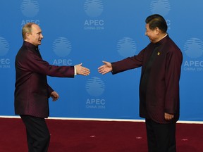 Russia's President Vladimir Putin (L) is welcomed by Chinese President Xi Jinping as he arrives for Asia-Pacific Economic Cooperation (APEC) Summit banquet at the Beijing National Aquatics Center in the Chinese capital on November 10, 2014.