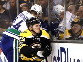 Erik Gudbranson #44 of the Vancouver Canucks checks Frank Vatrano #72 of the Boston Bruins into the boards during the first period at TD Garden on October 19, 2017 in Boston, Massachusetts.  The hit earned Gudbranson a one-game suspension.