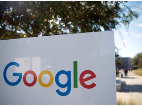 This file photograph taken on November 4, 2016, shows a cyclist riding past a Google sign and logo at the Googleplex in Menlo Park, California.