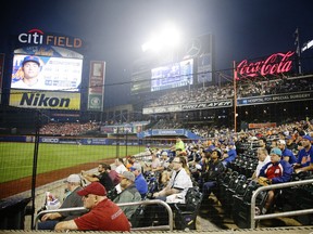 In this July 14, 2017 file photo fans watch from behind a net during the third inning of a baseball game between the New York Mets and the Colorado Rockies in New York.