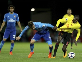 Watford's Abdoulaye Doucoure, right, and Arsenal's Mesut Ozil battle for the ball during their English Premier League match on Oct. 14.