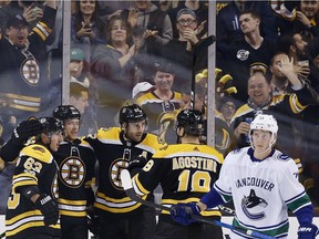 Bruins' Patrice Bergeron (37) celebrates with teammates from left, Brad Marchand; David Pastrnak and Kenny Agostino as Canucks' Troy Stecher (51) skates away during the third period of Vancouver's 6-3 drubbing by Boston Thursday night.