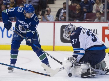 Vancouver Canucks #22 Daniel Sedin looks for the puck in front of Winnipeg Jets goalie Connor Hellebuyck in the first period of a regular season NHL hockey game at Rogers Arena, Vancouver, October 12 2017.