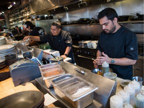 Line cooks Ishaan Kohli, right, and Abrahan Ruiz work in the kitchen at Edible Canada restaurant in Vancouver, B.C., on Wednesday October 11, 2017. The restaurant industry may be booming in British Columbia, but a combination of the high cost of living, tight profit margins and a shrinking workforce has made it difficult for kitchens to find enough staff. THE CANADIAN PRESS/Darryl Dyck