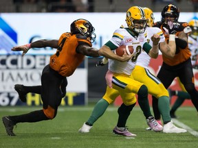 Edmonton Eskimos quarterback Mike Reilly, right, gets away from B.C. Lions' Alex Bazzie during the first half of a CFL football game in Vancouver, B.C., on Saturday October 21, 2017.