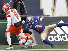 B.C. Lions' Anthony Thompson (8) and T.J. Lee (6) stop Winnipeg Blue Bombers' Weston Dressler (7) from holding onto a touchdown pass during the first half of CFL action in Winnipeg on Saturday.