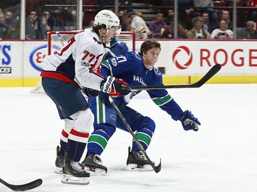 T.J. Oshie #77 of the Washington Capitals checks Ben Hutton #27 of the Vancouver Canucks during their NHL game at Rogers Arena October 26, 2017 in Vancouver, British Columbia, Canada.