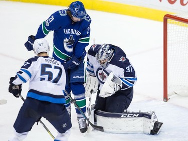 Winnipeg Jets' goalie Connor Hellebuyck, right, makes the save while being screened by Vancouver Canucks' Loui Eriksson (21), of Sweden, as Winnipeg's Tyler Myers (57) defends during the second period of an NHL hockey game in Vancouver, B.C., on Thursday October 12, 2017.