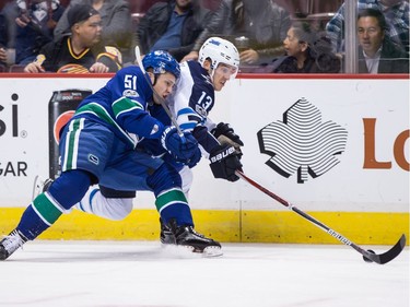 Vancouver Canucks' Troy Stecher, left, checks Winnipeg Jets' Brandon Tanev as he skates with the puck during the first period of an NHL hockey game in Vancouver, B.C., on Thursday October 12, 2017.