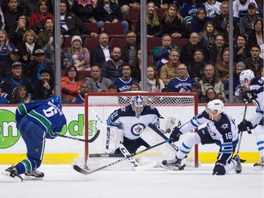 Winnipeg Jets' goalie Connor Hellebuyck, centre, stops Vancouver Canucks' Brock Boeser (6) as Winnipeg's Shawn Matthias (16) and Tyler Myers (57) defend during the first period of an NHL hockey game in Vancouver, B.C., on Thursday October 12, 2017.