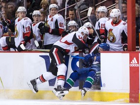 Alex Burrows checks Troy Stecher through the open door and into the Ottawa bench during the first period.