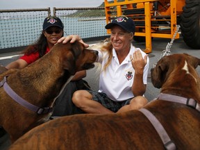 Jennifer Appel, right, and Tasha Fuiava sit with their dogs on the deck of the USS Ashland Monday, Oct. 30, 2017, at White Beach Naval Facility in Okinawa, Japan. The U.S. Navy ship carrying two sailors it rescued from their storm-battered sailboat in the Pacific docked Monday at the American naval base in Japan. Appel and Fuiava were standing with the USS Ashland's commanding officer and others high on the bridgeway when the ship arrived at the naval facility in Okinawa, five days after it picked up the women and their two dogs from their boat, 900 miles southeast of Japan.(AP Photo/Koji Ueda)