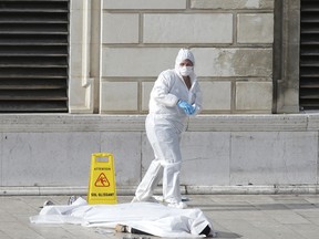 Investigative police officers work by a body under a white sheet outside Marseille 's main train station Sunday, Oct. 1, 2017 in Marseille, southern France.