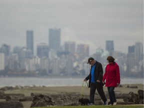 A couple walks their dog along Spanish Banks before the rain starts falling in Vancouver on Monday, Oct. 16, 2017.