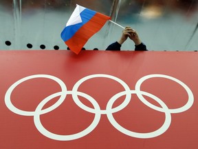 In this Feb. 18, 2014, file photo, a Russian fan holds the country's national flag over the Olympic rings.