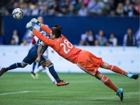 San Jose Earthquakes keeper Andrew Tarbell dives to punch the ball away from Whitecaps' Cristian Techera, back, during the second half of an MLS game in Vancouver on Sunday.