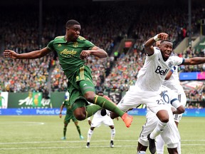 Portland Timbers defender Larrys Mabiala (33) and Vancouver Whitecaps forward Bernie Ibini (23) react after going for the ball during a corner kick in the first half at Providence Park.