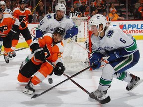 Shayne Gostisbehere and Brock Boeser battle for the puck during the third period at the Wells Fargo Center on Nov. 21, 2017.