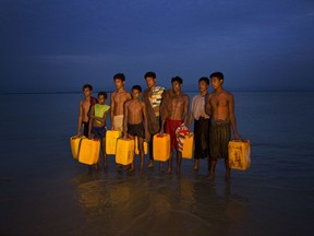 In this Nov. 5, 2017, photo, newly arrived Rohingya Muslims carry yellow plastic drums they used as flotation aids and listen to Bangladeshi authorities, not pictured, after swimming across the Naf river at Shah Porir Dwip, Bangladesh. The Naf river is a natural border between Myanmar and Bangladesh. Several young Rohingya Muslims escaping the violence in their homeland of Myanmar are now so desperate that they are swimming to safety into neighboring Bangladesh. (AP Photo/Bernat Armangue)