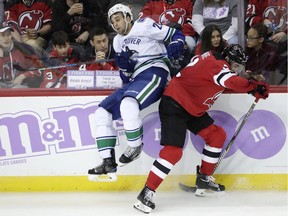 New Jersey Devils' defenceman John Moore, right, checks Vancouver Canucks' forward Brandon Sutter during the third period of Friday's NHL game in Newark, N.J. The Devils won 3-2.