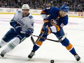 New York Islanders' Adam Pelech battles Sven Baertschi of the Vancouver Canucks for the puck during Tuesday's NHL action in New York.