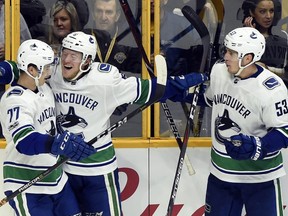 Vancouver Canucks Brock Boeser, centre, celebrates with Nikolay Goldobin, left, and Bo Horvat after Boeser scored the go-ahead goal against the Predators in the third period of Thursday's game in Nashville.