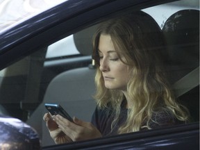 A driver uses her cellphone while sitting in traffic. The B.C. government announced Monday it will designate distracted driving a ‘high-risk driving behaviour’ and hike fees on offenders, effective next March 1.