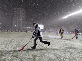 A worker clears snow from the field before the Grey Cup Sunday November 26, 2017 in Ottawa. The Toronto Argonauts will play the Calgary Stampeders in the 105th Grey Cup.