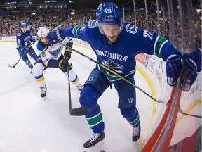Vancouver Canucks' Alexander Edler, front, of Sweden, kicks at the puck as St. Louis Blues' Chris Thorburn (22) reaches for it with his stick during the first period of Saturday's game in Vancouver.