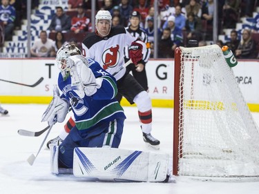 A shot sails above the crossbar and stays out of the net behind Vancouver Canucks goalie Jacob Markstrom as New Jersey Devils' Jimmy Hayes, back, watches during the first period of an NHL hockey game in Vancouver, B.C., on Wednesday November 1, 2017.