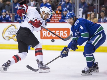 New Jersey Devils' Taylor Hall, left, has his shot blocked by Vancouver Canucks' Chris Tanev during the first period of an NHL hockey game on Wednesday.
