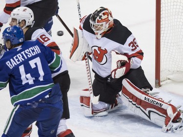 New Jersey Devils' goalie Cory Schneider makes a blocker save as Steven Santini (16) battles Vancouver Canucks' Sven Baertschi during the second period of an NHL hockey game on Wednesday.