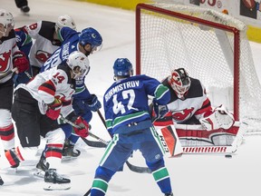 New Jersey Devils' goalie Cory Schneider, right, stops Vancouver Canucks' Alexander Burmistrov (42) as Sam Gagner (89) and New Jersey's Adam Henrique (14) defend during the second period.