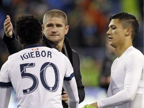 Vancouver Whitecaps head coach Carl Robinson reaches to give midfielder Nosa Igiebor a pat as striker Fredy Montero (right) watches after the Caps were eliminated from the MLS playoffs by the Seattle Sounders at Seattle’s CenturyLink Field on Thursday.
