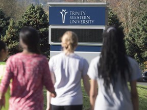 People walk past a sign at Trinity Western University in Langley.