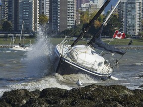 Waves and heavy wind pound a unmoored sailboat that washed ashore at Kits Point in Vancouver, October 17, 2017.