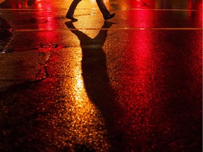Pedestrian walks across a street during a rainy night in Vancouver in January 2016.