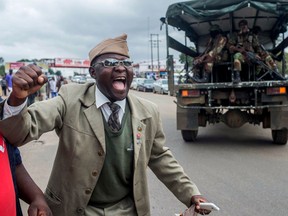 A Zimbabwean cheers as a military vehicle loaded with soldiers drives past him during a rally to demand the resignation of president Robert Mugabe on November 18, 2017, in Harare.