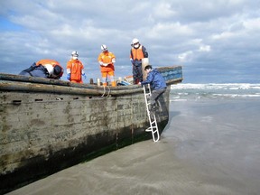 Coast guard officers inspect a battered wooden boat where eight bodies were found inside at a beach in Oga, Japan's Akita prefecture.