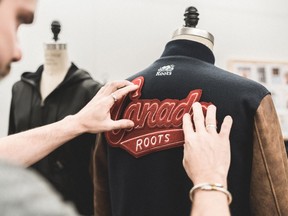A man works to apply a Canada patch on a Roots jacket.