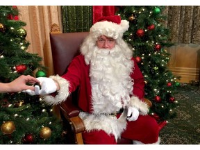 Premier John Horgan, playing Santa Claus, is pictured handing a lump of coal to a reporter during the Speaker's annual Christmas party, at the provincial legislature in Victoria on Wednesday, December 13, 2017.