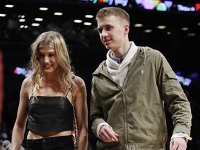 Genie Bouchard, walks the court with her blind date, John Goehrke, right, during the first half of an NBA basketball game between the Brooklyn Nets and the Milwaukee Bucks Wednesday, Feb. 15, 2017, in New York.