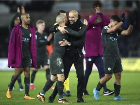 Manchester City manager Pep Guardiola, centre right, and star midfielder David Silva celebrate their victory against Swansea City, during their English Premier League match at the Liberty Stadium in Swansea, England on Wednesday, Dec. 13.