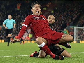 Liverpool's Roberto Firmino, left, and Swansea City's Martin Olsson battle for the ball during the English Premier League match at Anfield, Liverpool, England on Boxing Day.